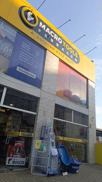 Fachada da Macro Tools Ferragem, com letreiro amarelo e produtos expostos na entrada